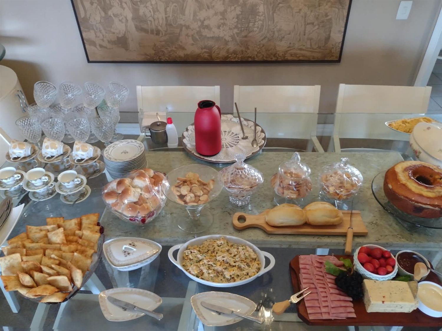 Mesa de café da tarde com pães, bolo, queijos e frios