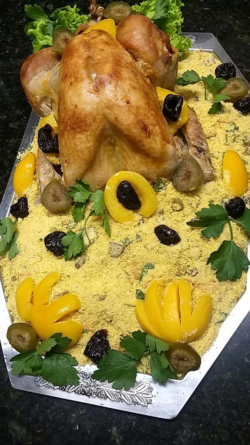 Frango assado inteiro sobre farofa dourada com frutas