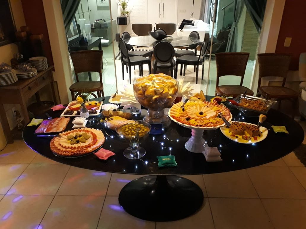 Mesa oval ao fim da tarde com buffet montado em sala de estar